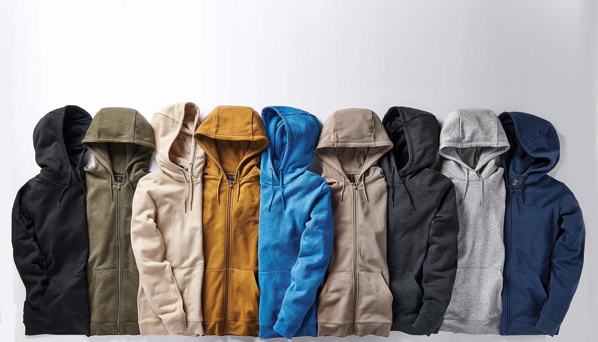 A row of nine hooded jackets in different colors is neatly arranged side by side against a white background, offering stylish solutions in black, olive green, beige, mustard yellow, blue, light brown, dark gray, light gray, and navy blue.