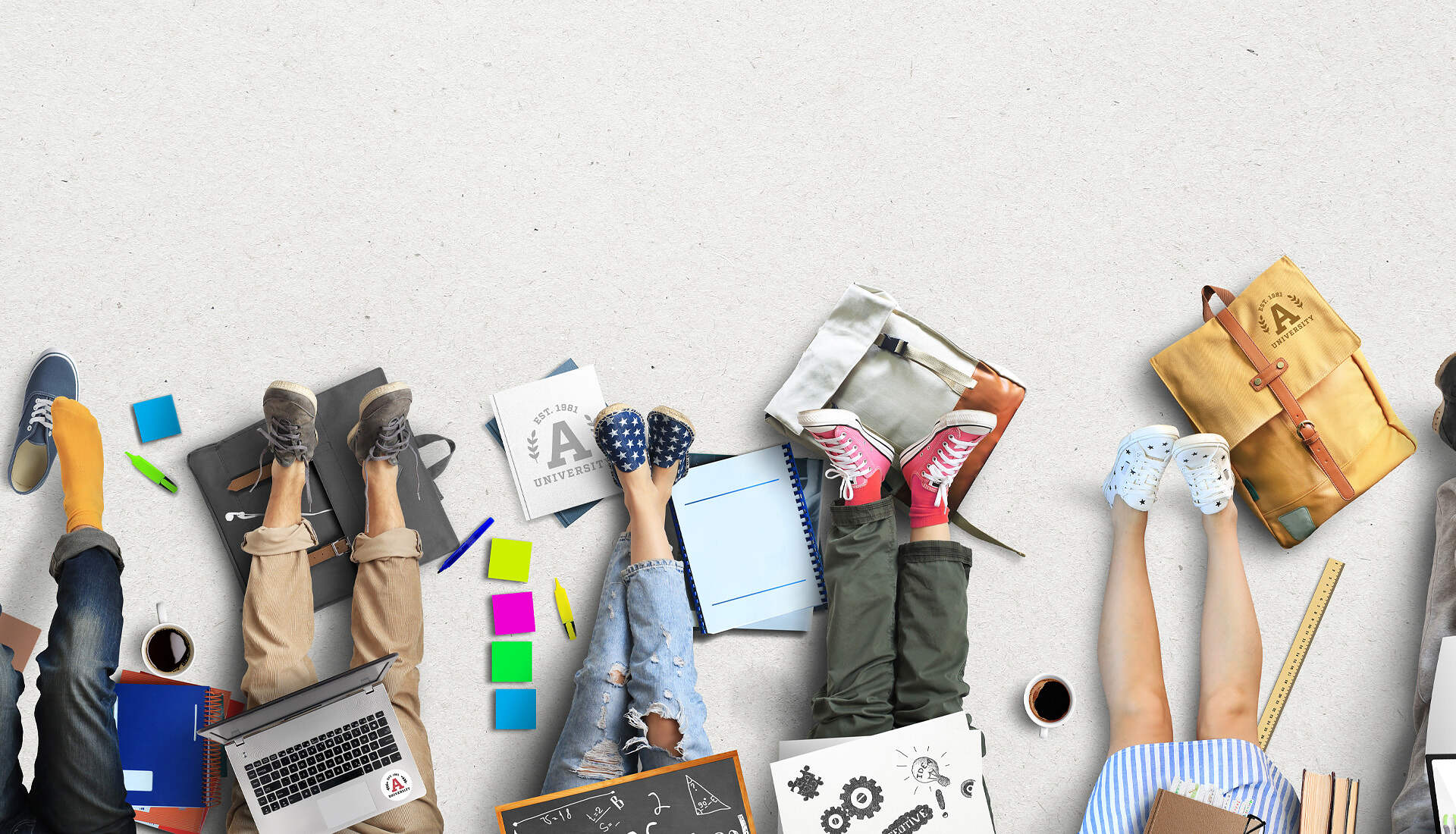 Seven people are lying on the ground with their legs outstretched, surrounded by laptops, notebooks, and various writing materials. Each person is wearing different types of footwear, ranging from sneakers to sandals. The scene has a casual, cooperative atmosphere akin to an open-air market of ideas.