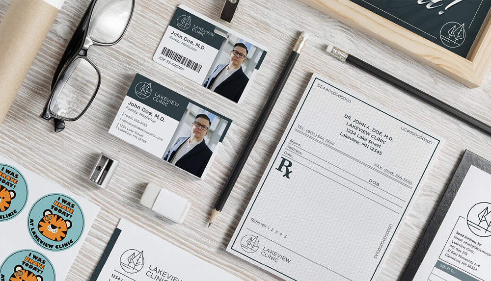 Assorted professional stationery items are neatly arranged on a desk—a business card, name badge, prescription pad, pencils, and more—each branded with "Lakeview Clinic." These essentials serve as perfect marketing tools featuring a doctor's name and photo.