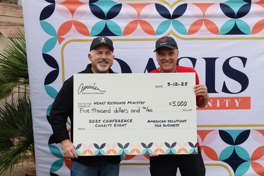 Two men proudly hold a large check for $5,000 made out to the Heart Response Ministry, standing before a vibrant "Oasis" banner. This generous donation stems from ASB’s recent charity events at the National Sales Conference, dated 3-12-25.