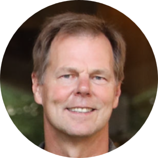 A middle-aged man with light brown hair smiles at the camera. Justin Buysse, Director of Distribution at American Solutions for Business, is photographed against a blurred, dark and natural background.